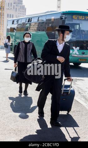 Jerusalem, Israel - 6. August 2020: Ein jüdisch-orthodoxes Paar mit COVID-Masken auf einer Straße in Jerusalem. Stockfoto