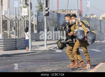 Jerusalem, Israel - 6. August 2020: Zwei israelische Soldaten, die viel Ausrüstung tragen und COVID-Masken auf einer Jerusalemer Straße tragen. Stockfoto