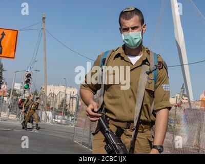 Jerusalem, Israel - 6. August 2020: Ein israelischer Kampfsoldat mit einer COVID Maske in Jerusalem. Zwei weitere Soldaten im Hintergrund. Stockfoto