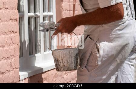 Hampshire, England, Großbritannien. 2020. Maler Dekorateur malen kleine Fenster auf einem ländlichen Haus. Maler Wasserkocher und Bürsten. Stockfoto