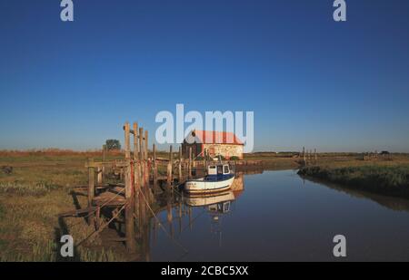 Ein Blick auf den Hafen mit Boot und alten Coal Barn an der North Norfolk Küste im Sommer in Thornham, Norfolk, England, Großbritannien. Stockfoto