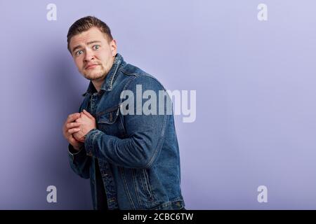 Junge emotional muskulösen Mann in Denim Jacke stehen mit ängstlichem Ausdruck, ist der Mann Angst vor Spinnen, Mäuse. Close up Seitenansicht Foto. Verkauf, di Stockfoto