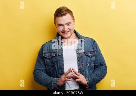 Schöner Mann hält Finger an Finger mit ernster Ausdruck Blick auf Kamera stehen über gelben Hintergrund, Plan, Idee. Nahaufnahme Porträt Stockfoto