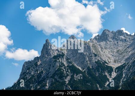 Alpen Berggipfel mit einer grünen Vegetation und das Blau wolkiger Himmel Stockfoto