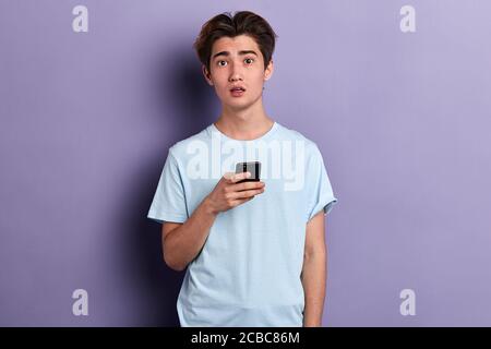 Unglücklich traurig deprimiert Mann hat sms mit schlechten Nachrichten erhalten, Kerl hat Probleme mit Handy, Nahaufnahme Porträt, isoliert blauen Hintergrund Stockfoto
