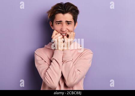 Nervöse Student beißen seine Nägel, warten auf Ergebnisse der Prüfungen. Nahaufnahme Foto. Isolierte blauen Hintergrund, Studio erschossen Stockfoto