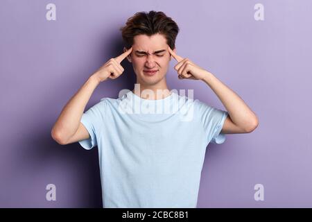 Verwirrt wütend Mann kann sich nicht an etwas erinnern. Guy berühren seinen Tempel mit den Fingern, massieren sie. Close up Porträt, isoliert blauen Hintergrund. Mann ha Stockfoto