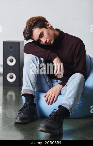 Traurige unglückliche depressive Mann sitzt im Musikstudio, voller Länge Foto. Einsamkeit Stockfoto