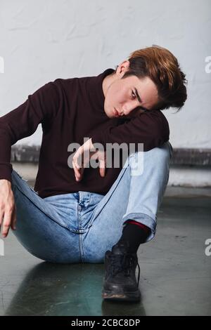 Unglücklicher trauriger Mann, der Strickpullover und Jeans trägt und sich auf den Arm lehnt und die Kamera anschaut. Nahaufnahme Stockfoto