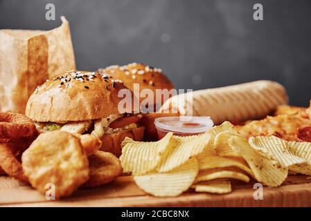 Ungesunde und Junk-Food. Verschiedene Arten von Fastfood und Snacks auf dem Tisch, Nahaufnahme. Essen zum Mitnehmen Stockfoto