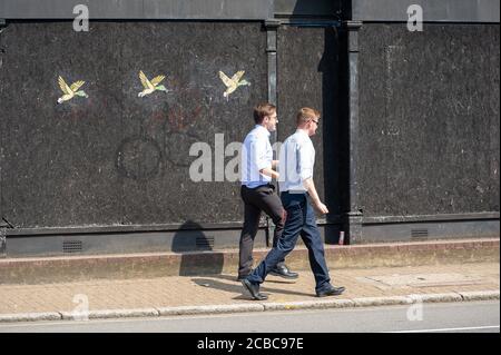Staines-upon-Thames, Surrey, Großbritannien. August 2020. Zwei Büroangestellte gehen am Markttag in Staines an einem vernagelten Laden vorbei. Quelle: Maureen McLean/Alamy Stockfoto