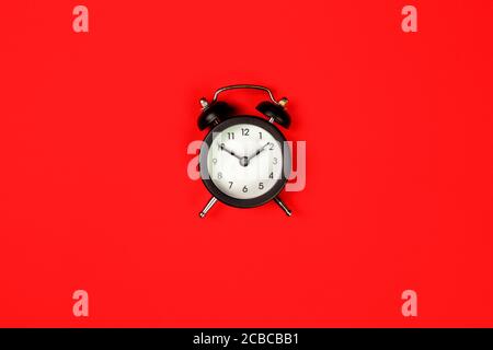 Isolierte schwarze Uhr auf rotem Hintergrund, Draufsicht Stockfoto