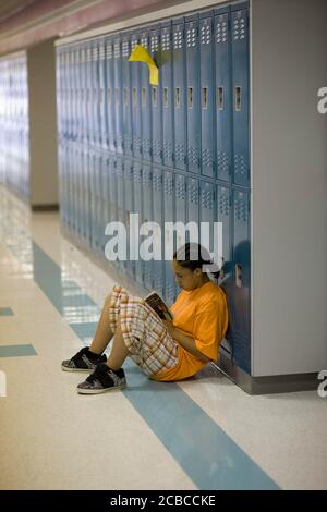 Pflugerville, Texas, USA, 30. Mai 2008: Schüler der siebten Klasse sitzt im Flur und liest ein Buch an der Park Crest Middle School, einem großen Vorstadtcampus in der Nähe von Austin mit 1.000 Schülern. © Bob Daemmrich Stockfoto