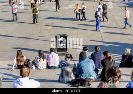 Rückansicht von Personen vor einem Schild mit der Aufschrift CCTV in Betrieb. Stockfoto