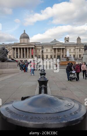 Touristen gesehen zu Fuß auf dem weiten Raum des Trafalgar Square mit dem National Gallery Museum im Hintergrund. Stockfoto