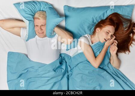 Ginger Frau schnarchen im Schlaf und blonde Mann leiden auf einem Bett. Draufsicht Foto. Close up Foto. Stockfoto