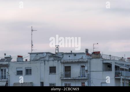 Kriegs-Luftangriffsssirene auf Wohngebäuden auf dem Dach. Alte pilzförmige Angriffsssirene, zwischen Antennen auf den Stadthäusern in Thessaloniki. Stockfoto