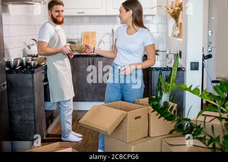 Junge kaukasische Ehepaar ziehen in eine andere Wohnung, sie glücklich auspacken Boxen zusammen. Glückliche Familie, Hauskonzept Stockfoto