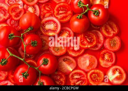 Tomatenscheiben Hintergrund mit zwei Zweigen von roten Tomaten in einem roten Hintergrund. Stockfoto