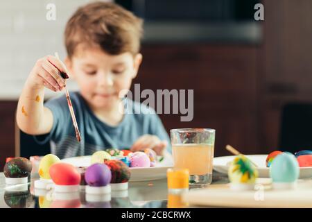 4-jährige Kaukasier junge hilft seiner Mutter mit Vorbereitungen zu Ostern. Konzentriertes Kind ist in der kreativen Tätigkeit, Malerei, Ostern Eier. chi Stockfoto