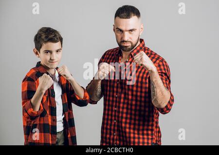 Papa und sein Sohn stehen in Boxposition. Nahaufnahme. Isoliert auf dem grauen Hintergrund. Sport, Hobby, Lifestyle Stockfoto