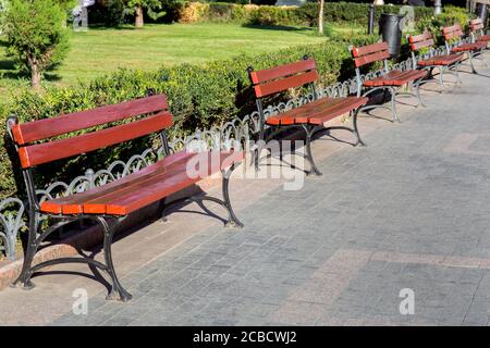 Die Reihe der Bänke auf dem Fußgängerweg im Parkgelände der Stadt, die leeren hölzernen Bänke niemand. Stockfoto