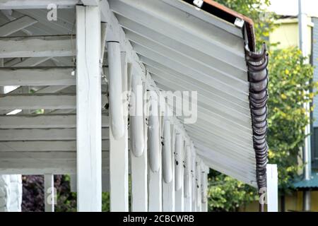 Dachvordach aus weißen Holzplanken und Stützen mit Sturmabläufen, Nahaufnahme der Struktur. Stockfoto