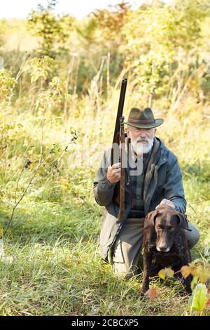 Senior Jäger und sein Hund im Wald, suchen nach Beute, Jagd auf wilde Tiere. Jagdsaison Stockfoto