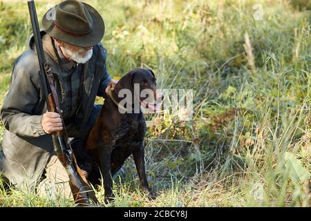 Senior Jäger und sein Hund im Wald, suchen nach Beute, Jagd auf wilde Tiere. Jagdsaison Stockfoto