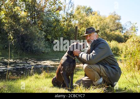 Pausenzeit nach der Jagd. Gute Arbeit, erfolgreiche Jagd auf See. Bärtiger Mann jagt auf Enten Stockfoto