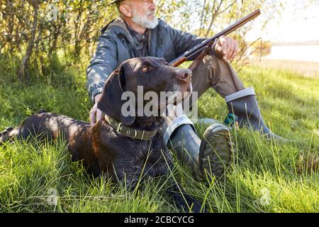 Auf der Suche nach Trophäe mit Hund. Älterer Mann bereit zur Jagd. Sitzen und ruhen vor der Jagd Stockfoto