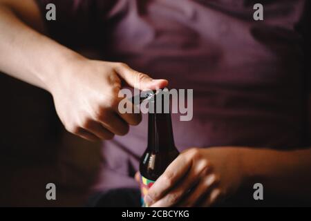 Junger Mann öffnet eine Flasche Bier Stockfoto