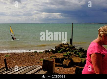 Windsurfer mit bunten Segeln auf der Solent vor der Küste von Strandgurnard Isle of Wight in einer steifen Brise unter Ein stimmungsvoller Himmel Stockfoto