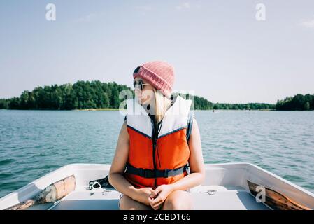 Frau, die im Sommer friedlich auf einem Ruderboot sitzt Ein See Stockfoto