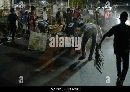 Larantuka, Indonesien. April 2015. Junge Männer machen Geräusche, indem sie Zinkplatten entlang der Straße ziehen, ein traditioneller Akt zum Gedenken an Rabu Trewa (Karwoche), ein Teil der Feierlichkeiten der Karwoche in Larantuka, Insel Flores, Indonesien. Stockfoto