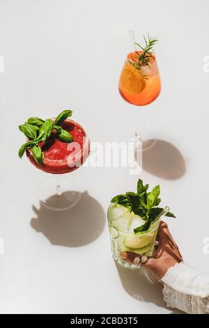 Aperol Spritz, Erdbeerbasil Margarita und Gin-Tonic in weiblicher Hand Stockfoto