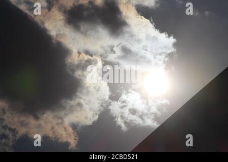 Hier ist ein kühnes Bild der starken Sonne am späten Nachmittag am Himmel. Die intensiv leuchtende Sonne. Einige Wolken - Cumuloform - haben eine orangefarbene Färbung. Stockfoto