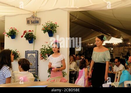 Ein Mädchen und ein Teenager im traditionellen spanischen Flamenco-Kleid in der Caseta El Salero während der Corpus Christi Fair 2019 in Granada, Spanien. Stockfoto