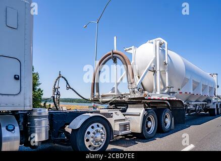 Big Rig weißen Industriediesel Langstrecke leistungsstarke Semi-Truck Traktor transportiert kommerzielle Fracht in speziell ausgestatteten runden Tank semi Trailer läuft Stockfoto