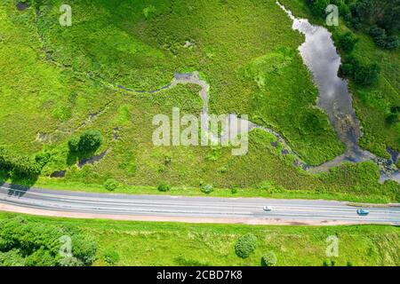 Grüne Landschaft mit kleinem Fluss und Straße. Ländliche Landschaft am sonnigen Sommertag. Luftbild Stockfoto