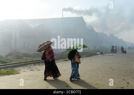 Dhaka, Bangladesch. 12. Aug, 2020. Frauen, die an einem Industriegebiet vorbeikommen, in dem die Luftverschmutzung flagrant.Dhaka kehrt nach einigen Monaten der anhaltenden Pandemie in sein normales Leben zurück. Kredit: SOPA Images Limited/Alamy Live Nachrichten Stockfoto