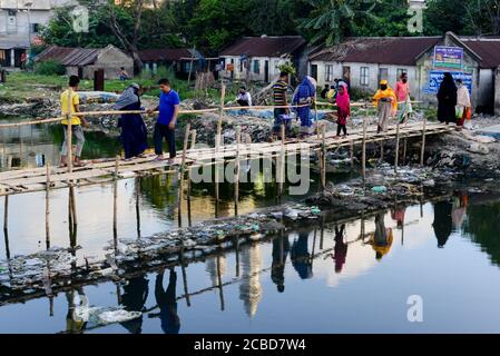 Dhaka, Bangladesch. August 2020. Menschen, die einen mit Industriemüll verschmutzten Fluss auf einer Bambusbrücke überqueren.Dhaka kehrt nach einigen Monaten der anhaltenden Pandemie in sein normales Leben zurück. Kredit: SOPA Images Limited/Alamy Live Nachrichten Stockfoto