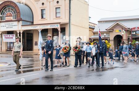 Charters Towers, Australien - 25. April 2019: Schulkinder marschieren am Anzac Day im Regen mit Kränzen und Mohnblumen Stockfoto