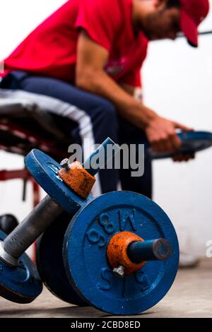 Junger Mann, der alte blaue Gewichte im Fitnessstudio auf den Boden hebt In einem Fitnessstudio Stockfoto