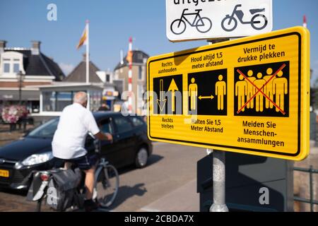 Gelbes Schild mit Text in niederländischer und deutscher Sprache mit einer 1.5-Meter-Warnung, bleiben Sie rechts und vermeiden Sie überfüllte Plätze durch Corona. Verkehr Stockfoto