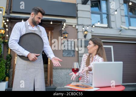 Unzufriedene Frau, die sich beim bärtigen Kellner über das Glas beschwerte Wein Stockfoto