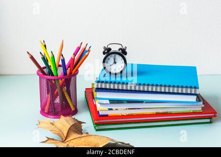 Zurück zur Schule Konzept. Bunte Stifte, Bücher und Wecker auf dem Tisch. Selektiver Fokus Stockfoto