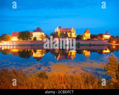 Malbork Schloss bei Nacht mit Reflexion in Nogat Fluss, Polen Stockfoto