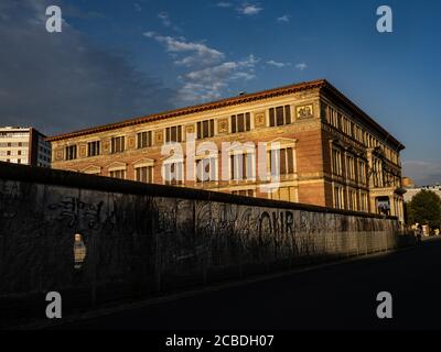 Berlin, Deutschland. August 2020. Der Martin-Gropius-Bau scheint im Licht der aufgehenden Sonne zu glühen, während der 200 Meter lange noch erhaltene Mauerabschnitt in der Niederkirchnerstraße noch im Schatten steht. Das denkmalgeschützte Gebäude markierte während der DDR die Grenze zwischen den Bezirken Mitte (Ost-Berlin) und Kreuzberg (West-Berlin). Heute vor 59 Jahren, am 13. August 1961, begann der Bau der Mauer. Quelle: Paul Zinken/dpa/Alamy Live News Stockfoto