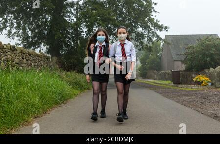 Camptoun, East Lothian, Schottland, Großbritannien, 13. August 2020. Rückkehr in die Schule: Die Zwillinge Louisa und Imogen, die vor zwei Tagen 12 Jahre alt wurden, brechen an einem trüben Morgen zu ihrem ersten Schultag im North Berwick High als S1-Schüler auf. Sie verpassten die normalen Induktionstage in P7 aufgrund der Sperre der Covid-19-Pandemie Stockfoto